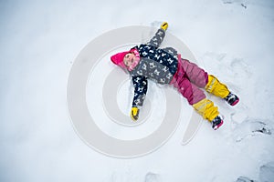 Cute girl making snow angel during winter.