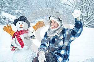 Cute girl making snowman on snowy field outdoor. Joyful Beauty young woman Having Fun in Winter Park.