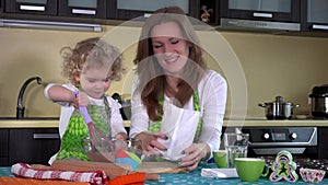 Cute girl with mother mixing chocolate flour in glass bowl on kitchen table