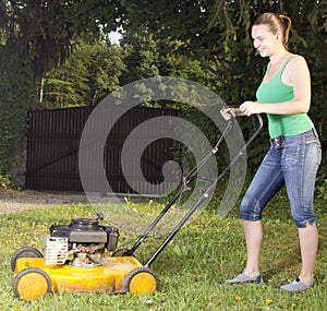 Cute girl moving the grass with yellow lawn mover