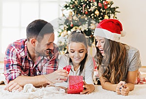 Cute girl opening a present on a Christmas morning with her family