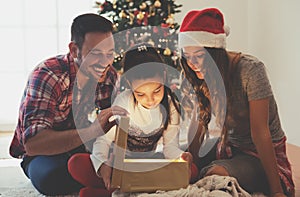 Cute girl opening a present on a Christmas morning with her family