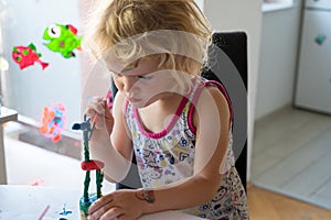 Cute girl painting wooden giraffe push puppet.