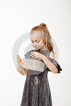 Cute girl in a party dress that opens a box with a gift