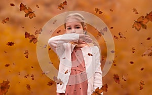 Cute girl with pigtails among the leaves in the forest