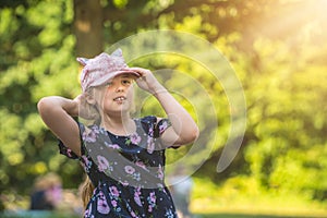 Cute girl in pink hat posing in a park