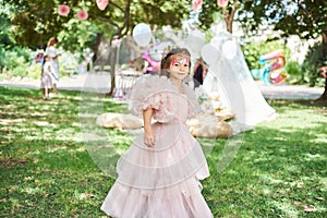 Cute girl in a pink puffy dress in the park