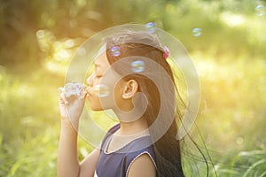 Cute girl play blowing bubble on playground with hard sun light. Little Kids enjoy and fun on play yard