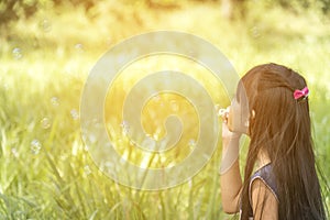 Cute girl play blowing bubble on playground with hard sun light. Little Kids enjoy and fun on play yard