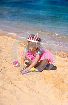 Cute girl playing with easter eggs on the beach