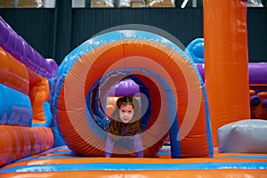 Cute girl playing on inflatable bounce house in entertainment center