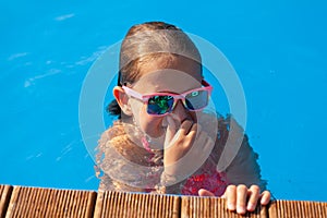 Cute girl playing in outdoor swimming pool. Summertime Fun.