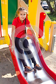 Cute girl playing on playground, having fun on a slide