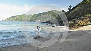 Cute girl is playing with waves at Yanui Beach under blue sky.