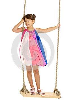 Cute girl playing on wooden swing