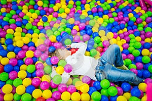 Cute girl plays in the pool with plastic balls