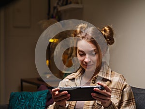 A cute girl with a portable game console plays a video game. Mobile games, modern technologies, cyberspace, virtual reality,