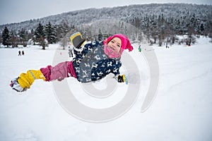Cute girl posing in fresh snow lying and waving.