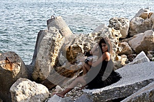 Cute girl posing on rocky boulders on the seashore