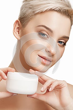 Cute girl preparing to start her day. She is applying moisturizer cream on face.