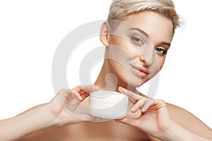 Cute girl preparing to start her day. She is applying moisturizer cream on face.