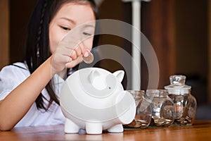 Cute girl putting money coins in piggy bank,saving money concept