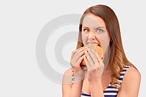 Cute girl quickly eats Burger, wrinkling nose