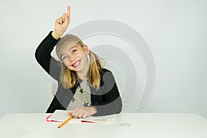 Cute girl is raising her hand in the classroom