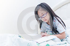 Cute girl reading book on bed