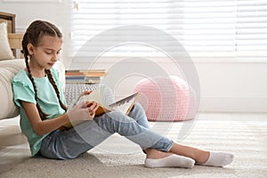 Cute girl reading book on floor at home