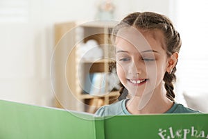 Cute girl reading book at home