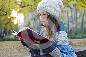 Cute girl reading book in the park at sunset