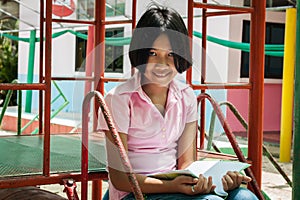 Cute girl reading book at playground