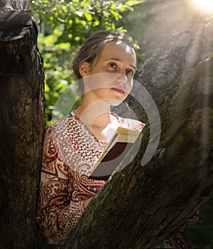 Cute girl reading a book under a tree