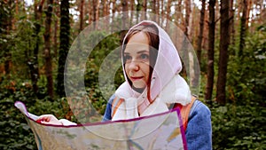 Cute girl reading map in forest. Traveling woman with backpack with open map in woods.