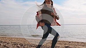 Cute girl in a red coat runs with her small siba inu dog during family rest near the ocean slow motion