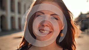 Cute girl with red hair and freckles on the street. Big city central street. Sunrise lighting.