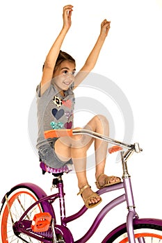 Cute girl riding a bicycle with her hands in the air