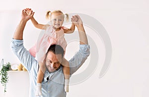 Cute girl riding on her father`s shoulders