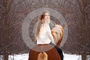 Cute girl riding horse looking back over shoulder