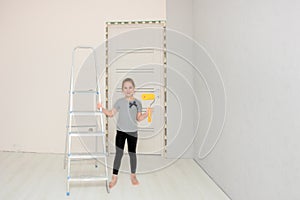 cute girl in the room where the renovation is underway stands next to the stepladder and holds a paint roller in her