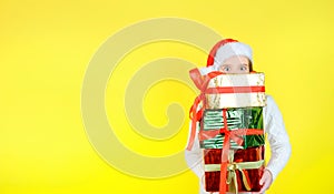 Cute girl in a santa claus checker holds gift boxes