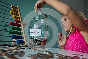 Cute girl saving money for education, child put coins into jar