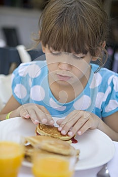 cute girl seven years old eats a pancake