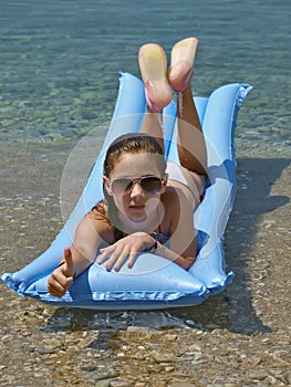 Cute girl showing thumb's up sign on sea