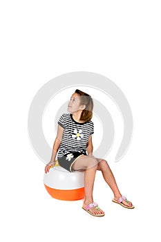 Cute girl sitting on beach ball waiting to play