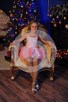 Cute girl sitting in a chair at the Christmas tree