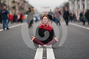 Cute girl sitting in meditation in the middle of a busy street.