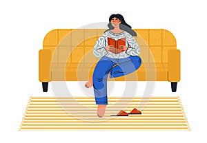 Cute girl sitting on a sofa and reading a book.