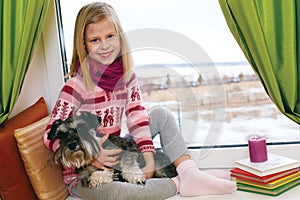 Cute girl sitting on a window sill with his dog